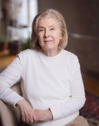 Woman wearing a white sweater sitting in a room with blurred background