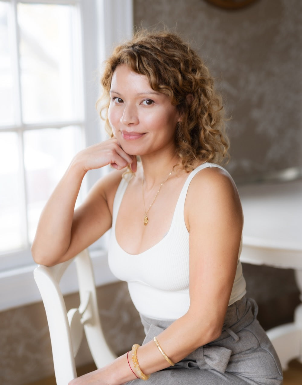 Woman sitting on a chair indoors with a neutral background