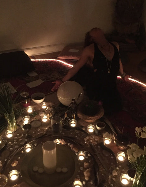 Person sitting at a table with candles and a bowl in a dimly lit room